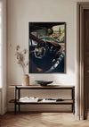 Een minimalistische kamer is voorzien van een ingelijst CollageDepot Bugatti Chiron Interior Schilderij dat boven een houten consoletafel hangt, gebruikmakend van een magnetisch ophangsysteem. Op de tafel staan gedroogde planten in een vaas, een ondiepe schaal en een open boek. Licht uit een nabijgelegen raam werpt zachte schaduwen door de kamer.