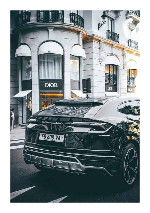 Een zwarte CollageDepot aaa 016 SUV geparkeerd buiten de Dior-winkel in een stadsstraat, toont het strakke ontwerp en de reflecterende oppervlakken van het voertuig, onderstreept door luxueuze architectonische details van het gebouw.-