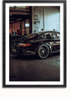 Ingelijste foto van een strakke zwarte Porsche GT3 geparkeerd in een slecht verlichte garage. De auto heeft grote lichtmetalen velgen en een achterspoiler. De algehele setting ziet er industrieel uit met gereedschappen en apparatuur zichtbaar op de achtergrond, waardoor het een prachtig stukje wanddecoratie is wanneer het wordt opgehangen met een magnetisch ophangsysteem. De "Porsche GT3 In Een Garage" van CollageDepot voegt een vleugje elegantie toe aan elke ruimte.,Zwart-Met,Lichtbruin-Met,showOne,Met