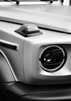 Close-up van CollageDepot's aaa 061 - koplamp en richtingaanwijzer van de auto in zwart-wit, wat het strakke ontwerp van de voorkant van het voertuig benadrukt.-