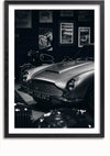 Een zwart-witfoto van een klassieke Aston Martin, tentoongesteld in een showroom of museumomgeving. De achtergrond is voorzien van ingelijste posters als wanddecoratie, waarbij een andere auto gedeeltelijk zichtbaar is. Op het kenteken van de auto staat "HKR 391D", en het is op elegante wijze gemonteerd met behulp van een klassiek Aston Martin-schilderij van CollageDepot.,Zwart-Met,Lichtbruin-Met,showOne,Met