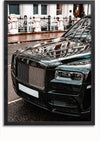 Een close-upbeeld van de voorkant van een zwarte luxe sedan staat geparkeerd op een natte straat. De auto heeft een opvallende grille, strakke koplampen en een glanzende buitenkant die nabijgelegen gebouwen weerspiegelt. Net als een Glanzende Zwarte Rolls Royce Phantom Schilderij van CollageDepot is de kentekenplaat wit en onleesbaar.,Zwart-Zonder,Lichtbruin-Zonder,showOne,Zonder