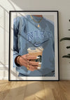 Een Coffee to go-schilderij met een persoon in een blauw Nike-sweatshirt, die een Starbucks-ijskoffie vasthoudt. Met verzorgde witte nagels en gouden sieraden, waaronder een ketting, rust dit ingelijste kunstwerk elegant op de hardhouten vloer. Perfect als wanddecoratie met het magnetische ophangsysteem van CollageDepot.