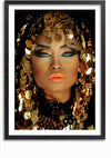 Een ingelijst portret van een persoon met uitgebreide make-up, feloranje lippenstift en blauwe oogschaduw. Gouden pailletten en kralen vallen uit hun prachtige gouden hoofdtooi, die het haar bedekt en het gezicht omlijst. De achtergrond is donker en benadrukt de levendige kleuren van dit opvallende CollageDepot The Arab Queen Schilderij.,Zwart-Met,Lichtbruin-Met,showOne,Met