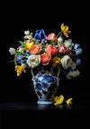 Een porseleinen vaas met een blauw en wit bloemdessin, de abb 001 - delfts-blauw van CollageDepot, bevat een arrangement van kleurrijke bloemen, waaronder gele tulpen, roze rozen, witte pioenrozen, blauwe irissen en diverse andere bloemen, afgezet tegen een zwarte achtergrond. achtergrond. Naast de vaas liggen enkele gele bloemen.-
