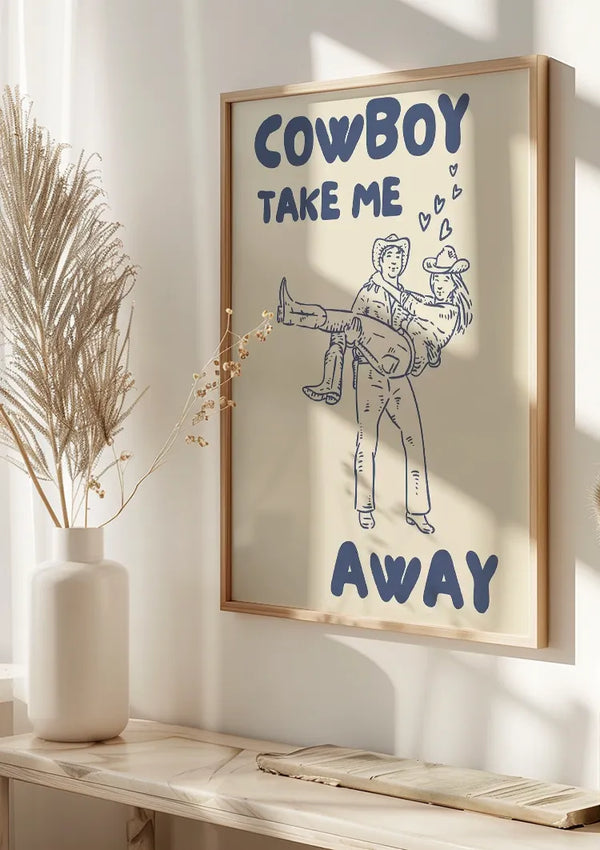 Een ingelijste tekening, Cowboy Take Me Away Schilderij van CollageDepot, toont een cowboy die een andere persoon in zijn armen draagt, omringd door hartillustraties. De tekst hierboven luidt: "Cowboy haal me weg." Dit charmante stukje wanddecoratie staat tegen een zonovergoten muur met siergrassen en een decoratieve vaas ernaast.,Lichtbruin