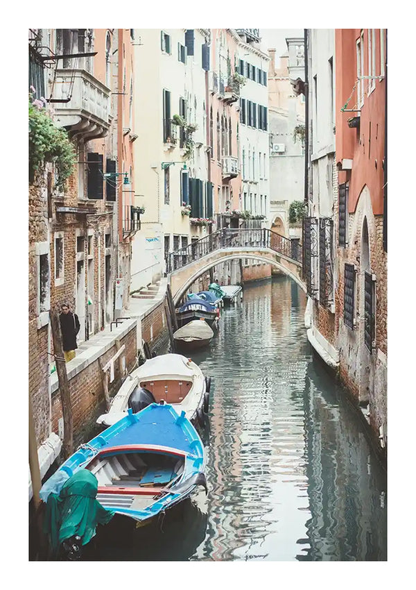 Smal kanaal in Venetië omzoomd met kleurrijke gebouwen. Langs de zijkanten liggen kleine boten aangemeerd en een stenen voetgangersbrug boog over het water. Deze scène, perfect voor een schilderij en wanddecoratie van Kanaal in Venetië van CollageDepot, toont typisch Venetiaanse architectuur en kalm water.