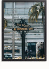 Op een straatnaambord staat "Via Rodeo" en "N. Rodeo Dr" voor een Louis Vuitton-winkel. Het bord, dat lijkt op een sierlijk Wegwijzer Louis Vuitton Winkel Schilderij met zwarte en gouden details van CollageDepot, staat trots. Op de achtergrond zijn palmbomen en de gevel van de winkel zichtbaar, waardoor een schilderachtig tafereel ontstaat.,Zwart-Zonder,Lichtbruin-Zonder,showOne,Zonder