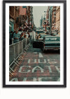 Een straatbeeld met een vintage zwarte auto geparkeerd op een weg gemarkeerd met 'BUS GATE'. De achterdeur van de auto staat open en mensen staan in een rij achter een metalen hek op het trottoir. Amerikaanse vlaggen en gebouwen sieren de achtergrond. Deze ingelijste foto zorgt voor een elegante wanddecoratie met een optioneel magnetisch ophangsysteem wanneer u kiest voor het Retro Street View USA Schilderij van CollageDepot.,Zwart-Met,Lichtbruin-Met,showOne,Met