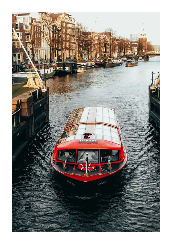 Een rood-witte Rondvaartboot In Amsterdam Schilderij van CollageDepot reist langs een gracht geflankeerd door gebouwen en bomen. De boot is gedeeltelijk bedekt met een glazen dak en de passagiers zijn van binnen zichtbaar. Het kanaal ligt vol met andere boten en erboven is een heldere hemel.-