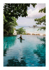 Een persoon met een strohoed drijft op een vlot in een overloopzwembad, met uitzicht op een rustig strand met weelderig groen en verre bungalows boven het water met de bbb 004 - natuur van CollageDepot.-