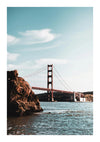 Golden Gate Bridge gezien vanaf het water met een prominente rots op de voorgrond onder een helderblauwe hemel.-