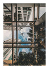 Een blik van onderen omhoog kijkend door een CollageDepot bbb 007 - natuur glazen plafondpassage omlijst door hoge gebouwen, met palmen en een vliegend vliegtuig zichtbaar door het transparante dak onder een heldere hemel.-