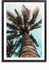 Een ingelijst CollageDepot Palmboom Vanaf De Onderkant Schilderij toont het opwaartse perspectief van een hoge palmboom tegen een bewolkte blauwe lucht. De bruine, getextureerde stam strekt zich naar boven uit met aan de bovenkant uitwaaierende bladeren. Op de achtergrond zijn extra palmbladeren zichtbaar, perfect voor prachtige wanddecoratie met zijn boeiende uitzicht.,Zwart-Met,Lichtbruin-Met,showOne,Met