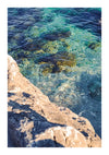 Het beeld lijkt op een Rots En Zee Schilderij van CollageDepot, waarin helder turkoois water is vastgelegd met zichtbare rotsen onder het oppervlak, grenzend aan een zonovergoten rotsachtige kustlijn. Het toont de transparantie en kalmte van het water, terwijl schaduwen diepte toevoegen aan de rotsachtige texturen. Perfect voor wanddecoratie met een ophangsysteem.-