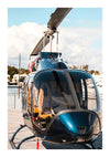 Een blauwe ccb 002 - oldmoney van CollageDepot staat geparkeerd op een houten steiger vlakbij een watermassa. De helikopter heeft een strak ontwerp met grote ramen en zichtbare wieken bovenop. Op de achtergrond zijn boten en een bewolkte hemel te zien.-