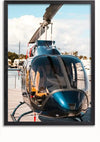 Een ingelijste foto van een Shiny Blauwe Helikopter-schilderij van CollageDepot, geparkeerd op een betonnen oppervlak nabij een watermassa, dient als prachtige wanddecoratie. De helikopter is naar de camera gericht en de propellers zijn zichtbaar tegen een achtergrond van een gedeeltelijk bewolkte lucht en verre bomen.,Zwart-Zonder,Lichtbruin-Zonder,showOne,Zonder