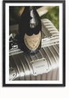 Een fles Dom Pérignon Vintage 2008 champagne wordt uitgestald op een zilveren RIMOWA-koffer. De afbeelding, ingelijst in zwart, dient als de perfecte wanddecoratie van CollageDepot, getiteld "Zilveren RIMOWA Koffer Schilderij.,Zwart-Met,Lichtbruin-Met,showOne,Met