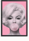 Een zwart-witfoto van een vrouw met blond haar die een kauwgombel blaast. De achtergrond is effen roze en de foto, gepresenteerd als een prachtig **Bubblegum Beauty Popart Schilderij van CollageDepot**, is ingesloten in een strakke zwarte lijst.