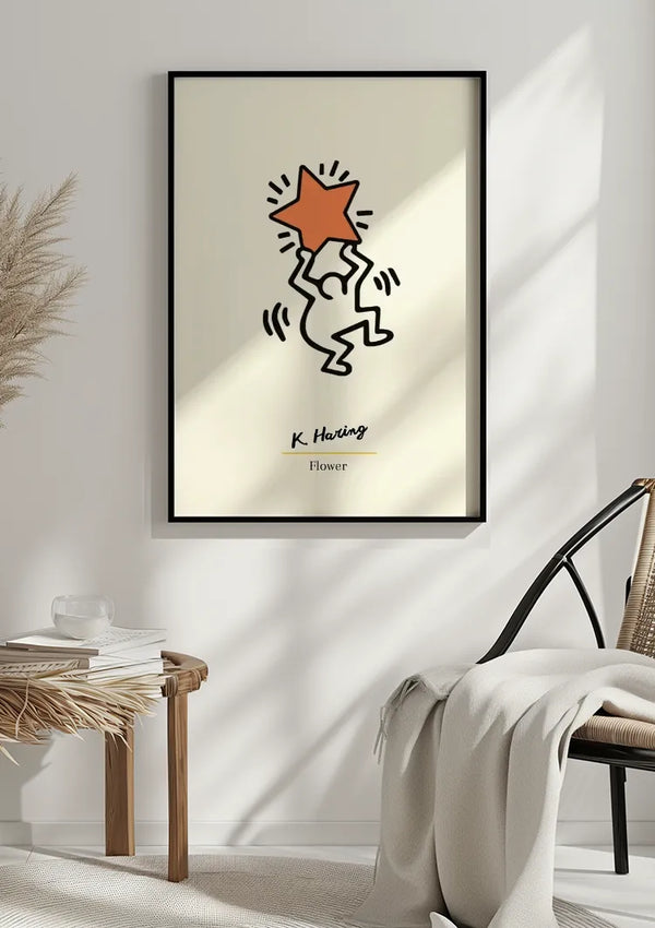 Aan een witte muur wordt een ingelijste wanddecoratie gehangen met een eenvoudige illustratie van een figuur die een ster vasthoudt. Onder de figuur zijn de handtekening "K. Haring" en de titel "Bloem" weergegeven. Vlakbij staat een houten tafel met een plant en een stoel met een witte deken eroverheen.Dit K. Haring - Een Grote Oranje Ster Schilderij van CollageDepot voegt een artistiek tintje toe aan elke kamer en brengt zowel kleur als intriges in uw decorruimte.,Zwart