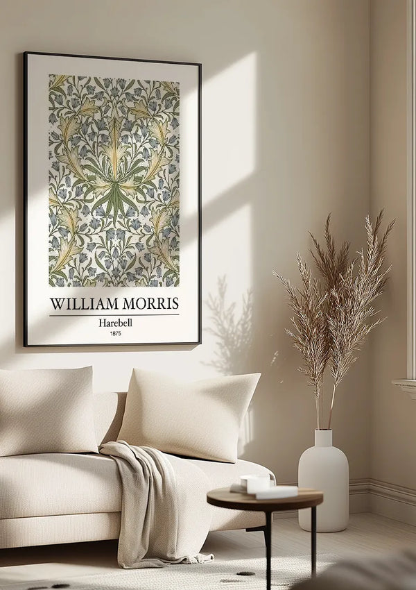 Een CollageDepot W. Morris Harebell Schilderij hangt aan een beige muur boven een crèmekleurige bank met kussens en een deken. Dit elegante stukje wanddecoratie is beveiligd met een magnetisch ophangsysteem. Naast de bank staat een bijzettafeltje met een vaas met daarin gedroogd blad.,Zwart