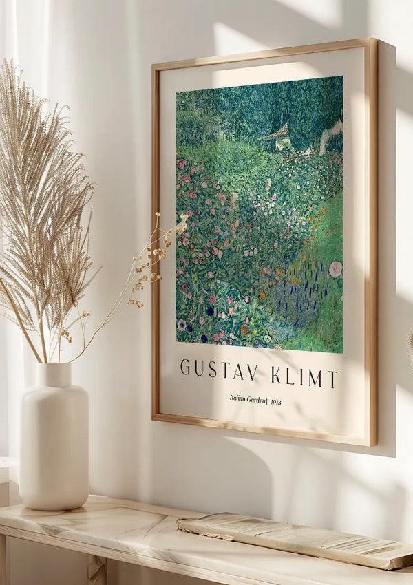 Een ingelijst kunstwerk met de titel "Italiaanse tuin" van Gustav Klimt, 1913, hangt aan de muur. De afbeelding toont een weelderige tuin met verschillende bloemen. Hieronder staat een witte vaas met gedroogde bloemen op een lichte houten plank. Zonlicht stroomt door een nabijgelegen raam en verlicht het prachtige Gustav Klimt Italian Garden Schilderij van CollageDepot.,Lichtbruin