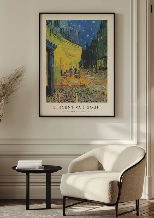 Een ingelijst CollageDepot V. Van Gogh Nachttafereel Terras Schilderij hangt aan een witte muur boven een moderne, gebogen witte stoel en een klein zwart bijzettafeltje in een goed verlichte, minimalistische kamer, wat een boeiende wanddecoratie aan de ruimte toevoegt.,Auto