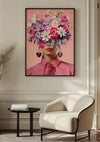 Aan de muur hangt een ingelijst Pink Flower Lady-schilderij van CollageDepot. Het toont een persoon in een roze topje met grote bungelende oorbellen, wiens gezicht verborgen wordt door een boeket van verschillende bloemen. Onder deze wanddecoratie staat een moderne lichtgekleurde stoel en een klein rond zwart tafeltje.,Zwart