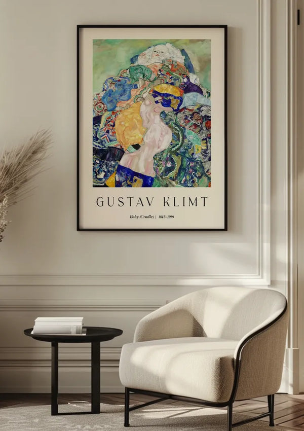 Een ingelijst CollageDepot Gustav Klimt Baby (Cradle) Schilderij hangt aan een muur boven een moderne witte fauteuil en een rond zwart bijzettafeltje in een zacht verlichte kamer. Het schilderij bevat abstracte figuren en levendige kleuren. De titel op de poster luidt "Gustav Klimt" met daaronder een aanvullende tekst.,Zwart