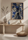 Een minimalistische kamer is voorzien van een houten consoletafel met een beige kussen op de vloer. Op de tafel staan twee vazen, een kleine pot en een stapel boeken. Boven de tafel hangt het ingelijste kunstwerk van CollageDepot, voorstellende een vrouw met een hoofddoek tegen een bloemenachtergrond, genaamd "aab 336 Delfts blauw.,Lichtbruin