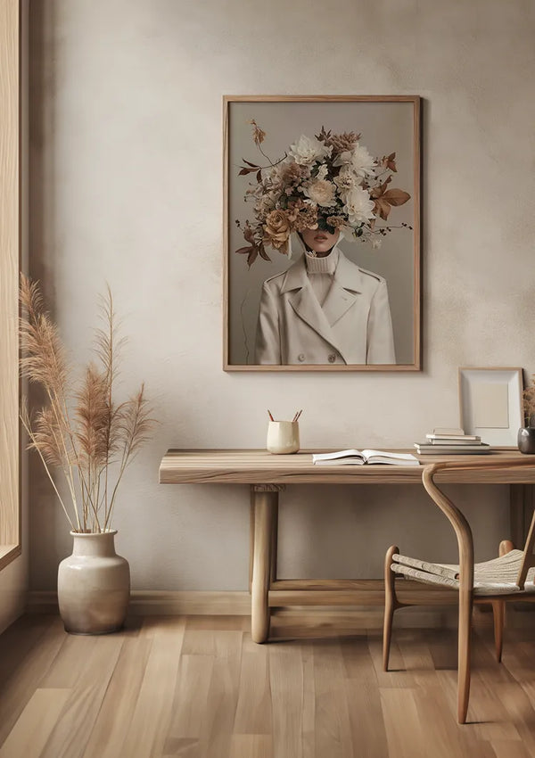 Een minimalistische kamer met een houten bureau met een stoel, een potplant en een ingelijst bloemstuk-gezichtsschilderij van CollageDepot aan de muur. Het schilderij toont een persoon in een beige coltrui met zijn hoofd verborgen door een groot boeket bloemen. De kamer heeft neutrale tinten en houten vloeren.,Lichtbruin
