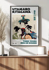 Een ingelijste print van Utamaro Kitagawa's kunstwerk getiteld "U. Kitagawa Three Young Men Or Women Schilderij" van CollageDepot, met drie figuren in traditionele Japanse kleding, wordt tentoongesteld op een houten plank tegen een witte muur, wat een elegant tintje geeft aan je wanddecoratie.,Zwart