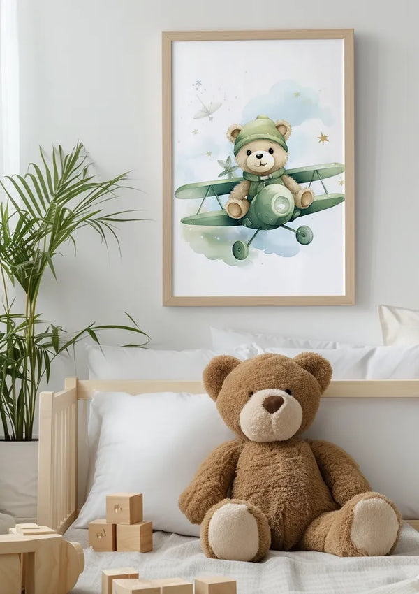 In een gezellige kinderkamer hangt een ingelijst CollageDepot Teddybeer Met Een Groene Vliegtuig Schilderij aan de muur met een magnetisch ophangsysteem. Onder de foto zit een grote teddybeer op een wit bed met houten blokken ernaast, en links staat een groene plant.,Lichtbruin