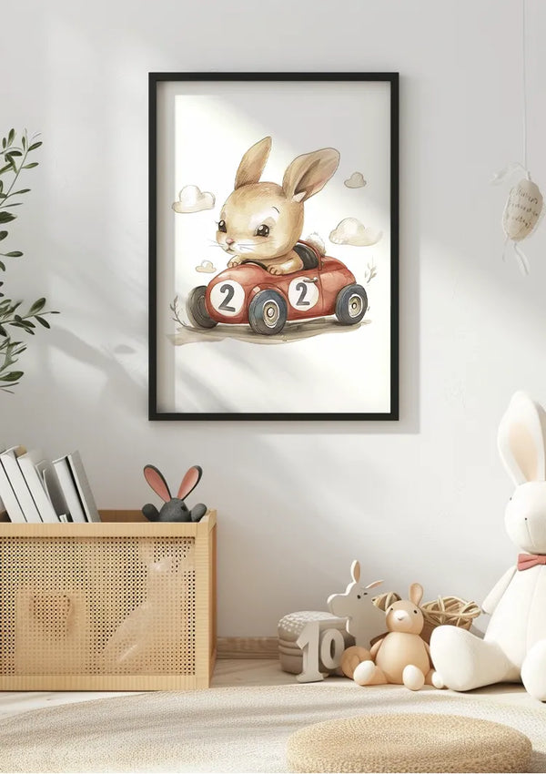 Aan een witte muur hangt een ingelijst Konijn In Rode Raceauto Schilderij van CollageDepot van een konijn dat een rode speelgoedauto bestuurt met het nummer 2 op de zijkant. Beneden staat een rieten mand met knuffels, en op de grond ligt een groot wit konijnenknuffeldier. Rechts bevindt zich een kleine hangende decoratie.,Zwart
