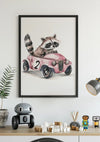 Een ingelijst Wasbeer Met Roze Vintage Auto Schilderij van CollageDepot op een witte muur met een aquarelillustratie van een wasbeer die in een roze auto rijdt met het nummer 2 erop. Onder de foto staat een plank met een speelgoedrobot, een potplant, blokken en een lamp. Het vintage design voegt charme toe aan elke ruimte, versterkt door het magnetische ophangsysteem.,Zwart